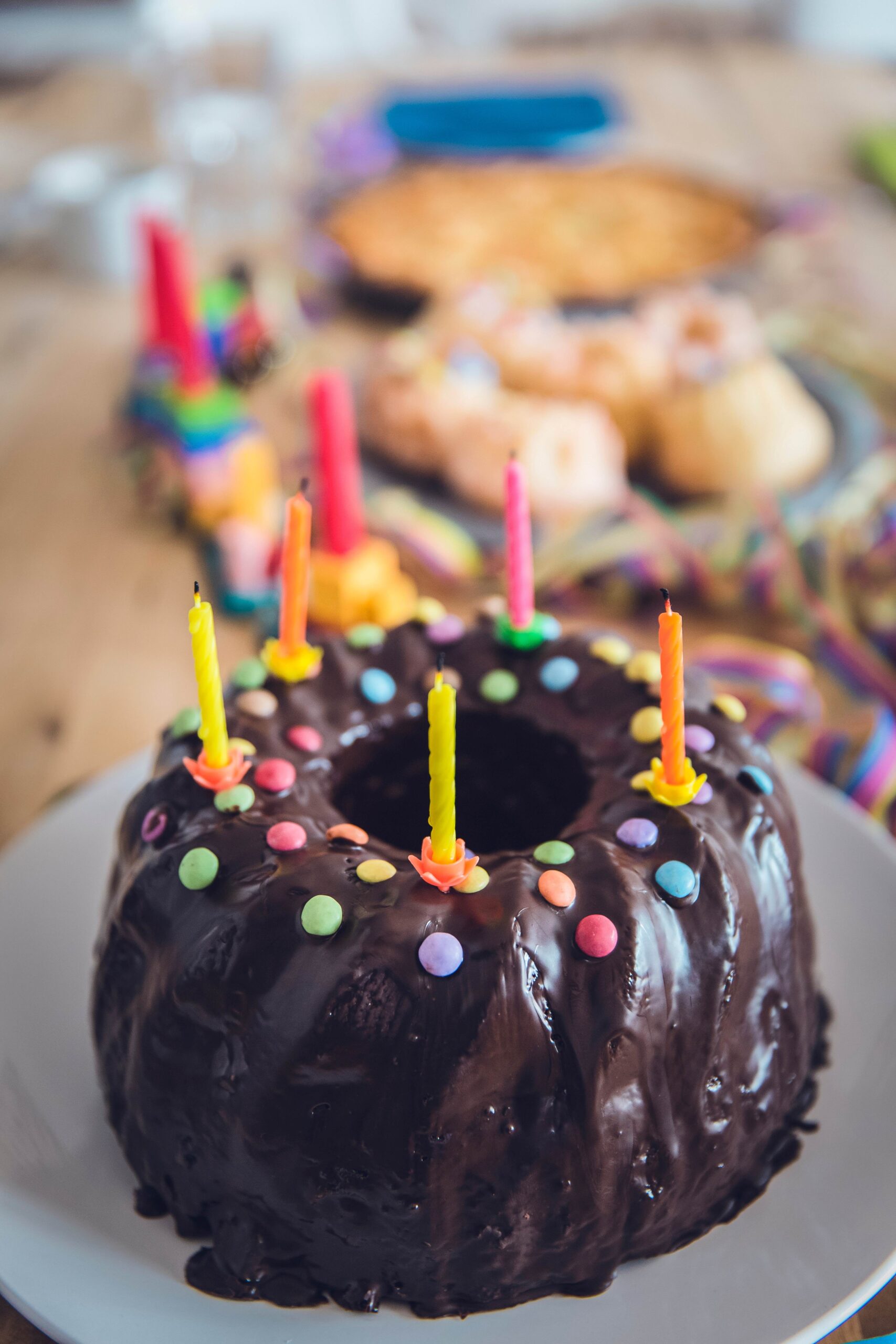 15 Jahre IEGUS: Bild eines mit Schokolade und Smarties dekorierten Gugelhupf auf einem Geburtstagstisch. Auf dem Kuchen sind Kerzen.